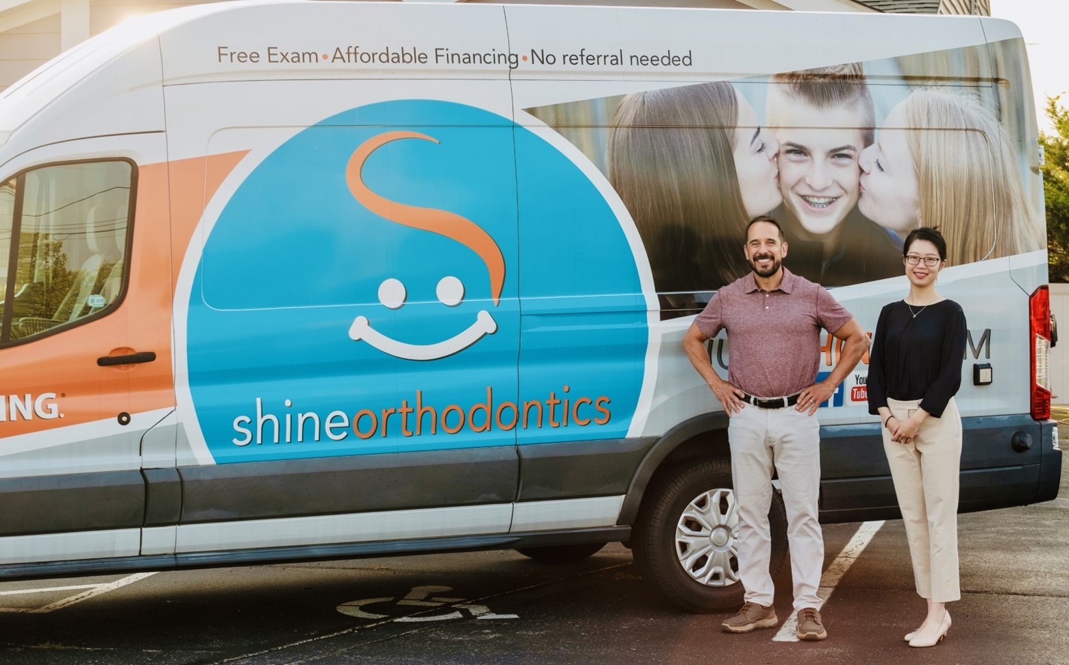 A man and woman smiling standing next to a company van 